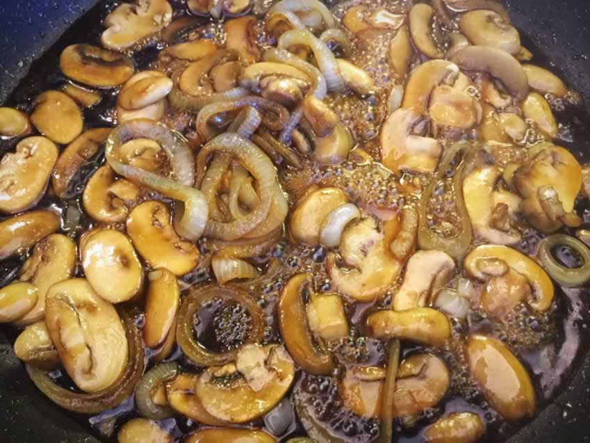 Sautéing the onions and mushrooms in the whiskey glaze