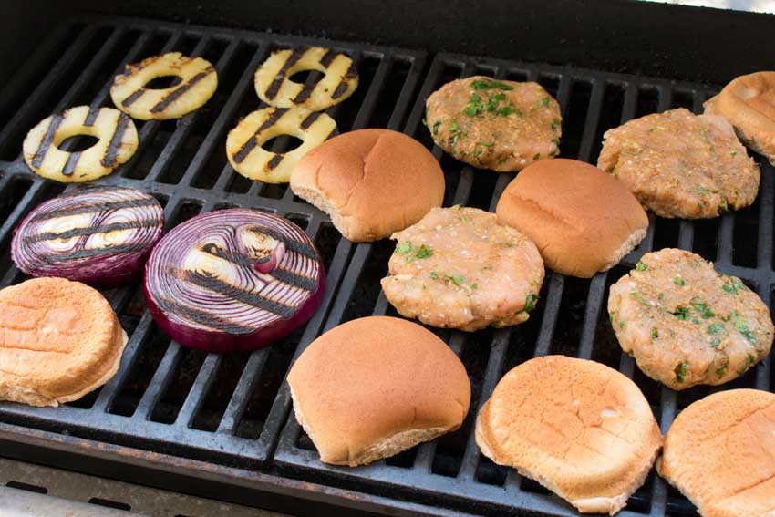 Grilling the burgers, pineapple, onions, and buns