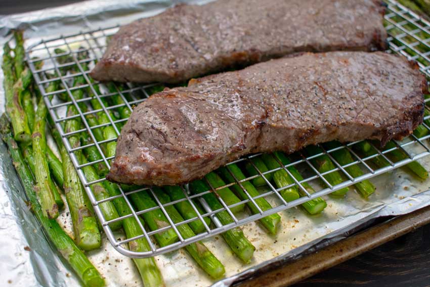 Broiled steaks and asparagus on a foil-lined sheet pan