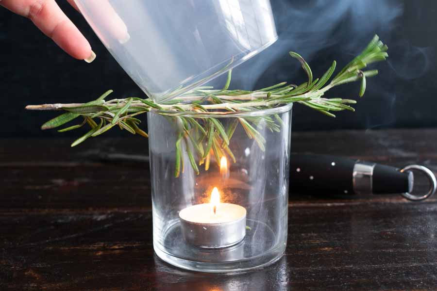 Capturing the rosemary smoke in a cocktail glass