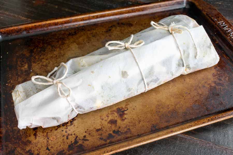 The salmon filet wrapped in parchment paper secured with kitchen string