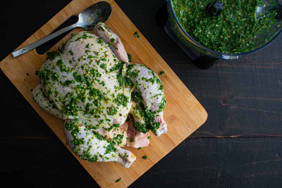 Covering the chicken in chimichurri sauce before roasting