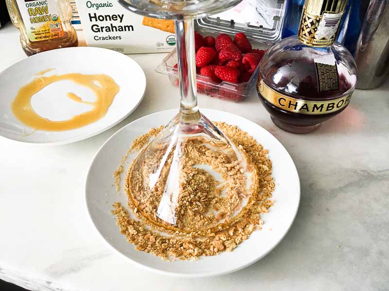 Rimming a martini glass with honey and graham cracker crumbs