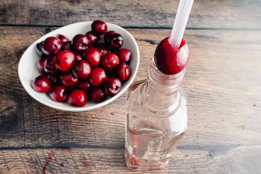 Pitting the cherries with a drinking straw and a bottle