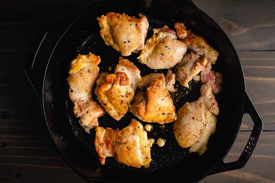 Browned chicken thighs in a cast-iron pan