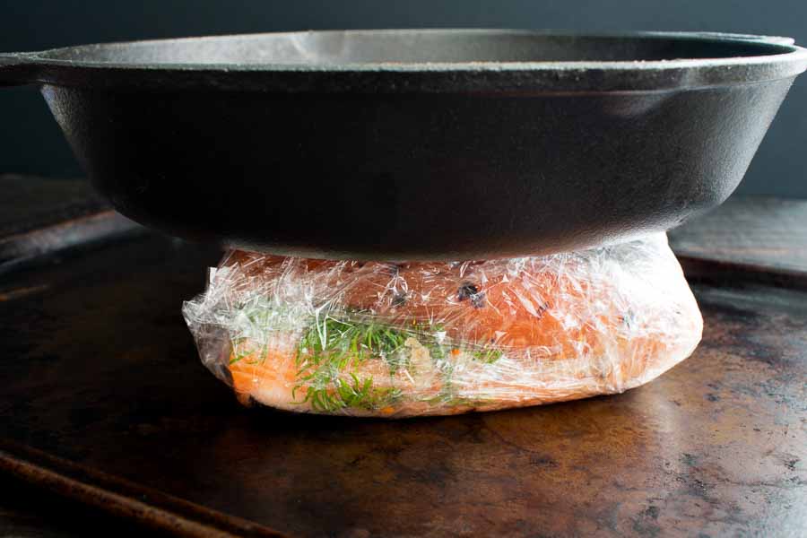 The seasoned salmon fillets stacked, wrapped, and weighted