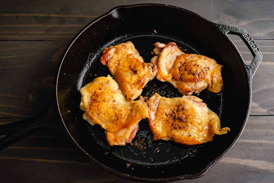 Frying the chicken thighs in a cast-iron skillet