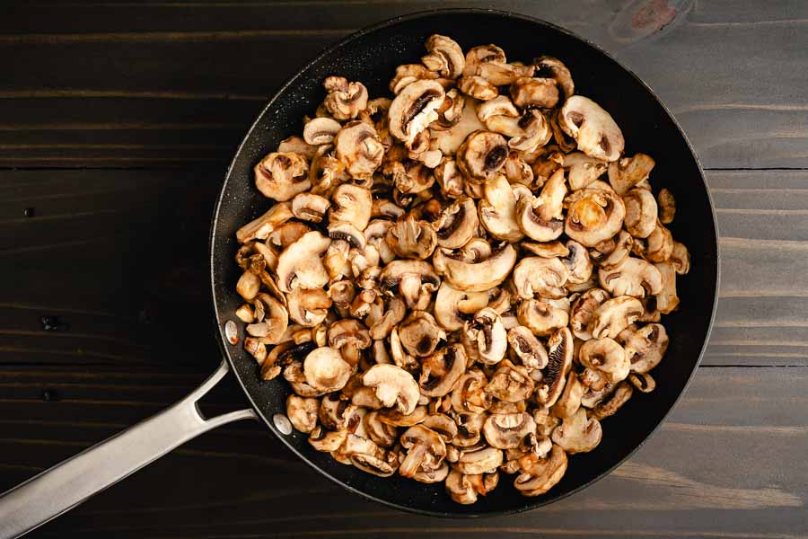 Sliced button mushrooms in a large skillet