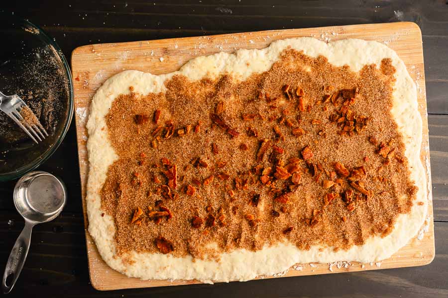 Rolled out dough topped with brown sugar, spices, and crumbled bacon