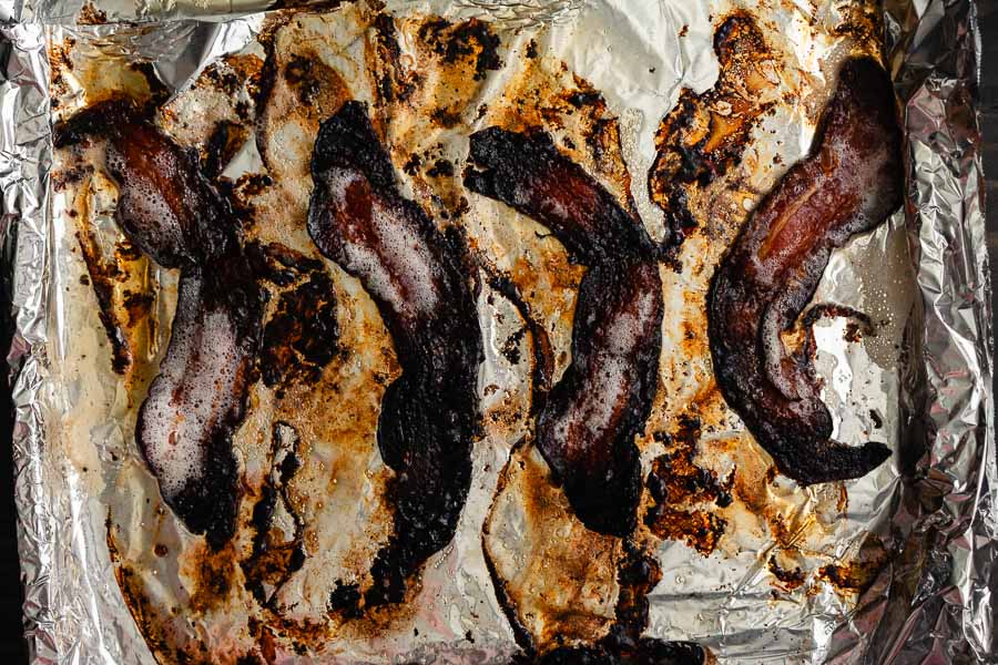 Overcooked bacon on a foil-lined sheet pan